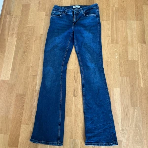 Blå bootcut jeans från Zara - Snygga blå jeans från Zara i klassisk bootcut-modell. Jeansen har fem fickor, normal passform och är tillverkade i ett mjukt denimtyg. Perfekta för dig som gillar en tidlös look med lite utsvängda ben.