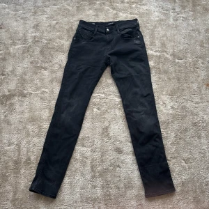 Svarta Replay Anbass jeans, storlek 30 - Säljer ett par svarta Replay Anbass jeans i storlek 30. Jeansen är i mycket bra skick och har inget som är trasigt på dom