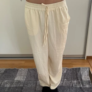 Vit/beiga linnebyxor? med snörning från H&M - Säljer ett par vita/beiga linnebyxor. Byxorna har raka ben och sidfickor, perfekta för en chill och avslappnad look. Lätta och luftiga, passar grymt till sommaren. Materialet är lite glansigare och mjukare än vanliga linnebyxor, så de sitter och faller lite som silkesbyxor. 