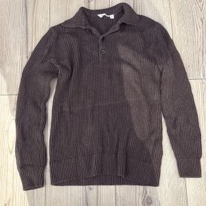 Brun ribbstickad tröja från Dobber - Mysig brun ribbstickad tröja från Dobber med krage och två knappar vid halsen. Långärmad och i klassisk modell som passar perfekt till jeans eller kjol. Tröjan har en skön avslappnad och är tillverkad i stickat material. Använd en gång köptes för 800