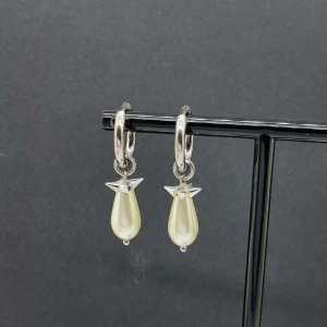 Silverörhängen med pärldroppar - Snygga örhängen i silverfärg med hängande droppformade pärlor och små detaljer som liknar vingar. Perfekt för dig som gillar unika smycken med en elegant touch. Passar till alla tillfällen och ger en cool vibe till din outfit.