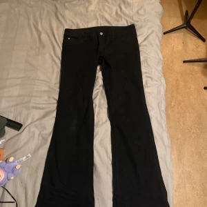 Svarta bootcut jeans Cheap Monday Booty Bei - Svarta jeans från Cheap Monday med klassisk femficksdesign och bootcut-ben. Snyggt broderad logga i rosa på bakfickan. Jeansen har normal passform och är tillverkade i ett stretchigt bomullsmaterial för extra komfort. Har själv strl 36/38 i Zara jeans och tycker att dessa passar bra eftersom svart jeans tyg brukar oftast passa mindre i storleken.