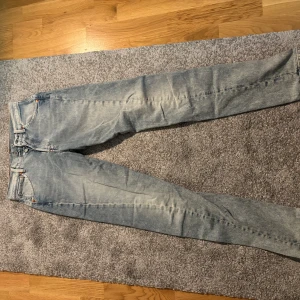 Levi's 512 ljusblå jeans W27 L32 - Säljer ett par Levi's 512 jeans i ljusblå tvätt med klassisk femficksdesign och röd patch bak. Jeansen har slim passform med något avsmalnande ben och är tillverkade i mjukt denimtyg. Perfekta för en avslappnad och trendig look.