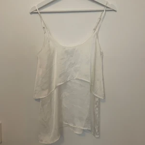 Vit linnetopp från Rut&Circle - Säljer en vit linnetopp från Rut&Circle i storlek 34. Toppen har tunna justerbara axelband och dubbla lager tyg som ger en snygg och luftig känsla. Perfekt till varma dagar och enkel att styla med jeans eller kjol. Går att pruta. Använd 1 gång 