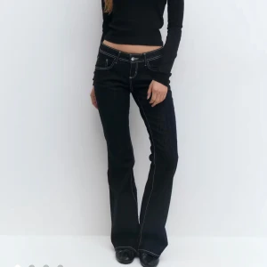 Nya low waist blå jeans  - Oanvända, mörkblåa, flared, low waist jeans, med en vit söm från Gina Tricot
