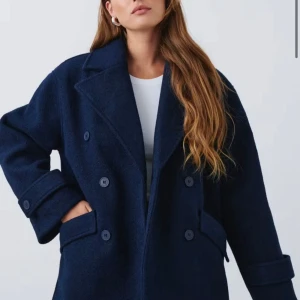 Mörkblå skepparkavaj från Gina Tricot - Snygg mörkblå skepparkavaj från Gina Tricot med dubbelknäppning och bred krage. Jackan har stora fickor framtill, uppvikta ärmslut och en oversized passform som ger en cool och avslappnad look. Perfekt för dig som gillar klassisk stil med modern twist.