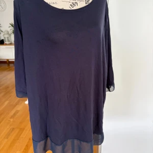Mörkblå blus från Å Plus, 2XL - Snygg mörkblå blus från Å Plus i storlek 2XL. Blusen har trekvartsärm med transparent meshdetalj vid ärmslut och nederkant, vilket ger en cool kontrast. Rund halsringning och loose passform gör den chill och enkel att styla med dina favoritjeans.