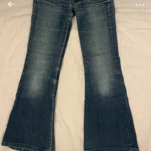 Blå bootcut jeans från Pepe Jeans - Snygga blå bootcut jeans från Pepe Jeans med slitningar och klassiska fem fickor. Jeansen har låg midja, breda benslut och coola detaljer på bakfickorna. Perfekta för dig som gillar en avslappnad och trendig look. Bilderna är från tjejen jag köpte byxorna ifrån 