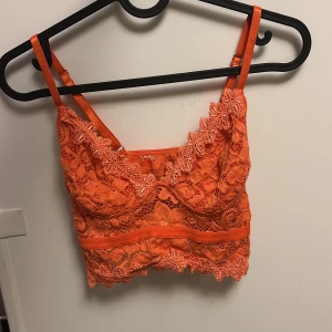 Orange spetsig linnetopp från SHEIN - Superfin orange linnetopp från SHEIN i spets med blommiga detaljer och smala axelband. Croppad modell med snygg kant nertill och genombrutet mönster som ger en cool vibe. Perfekt för dig som vill sticka ut med färg och stil.