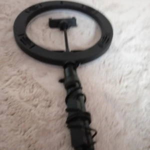 Ring light med mobilhållare - Säljer en svart och vit ring light med justerbar mobilhållare och fjärrkontroll på sladden. Perfekt för att få till det bästa ljuset när du sminkar dig eller tar selfies. Lampan har flera ljuslägen och styrs enkelt med knappar på sladden.