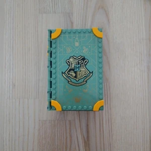 Hogwarts LEGO Bok - Cool bok i LEGO-format med Hogwarts-emblem på framsidan. Inuti finns minifigurer som påminner om karaktärer från en magisk värld. Perfekt för dig som gillar fantasy, magi och att bygga med LEGO. En unik samlarpryl för unga fans av äventyr och berättelser. Skriv privat för fler bilder eller frågor.