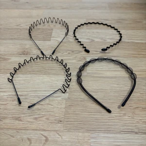 Svarta metall-diadem med vågig design - Fyra svarta diadem i metall med olika vågiga och spiralformade designer. Perfekt för att ge frisyren en cool och edgy touch. Alla har svarta plaständar för extra komfort bakom öronen. Snygga detaljer och passar till många stilar.