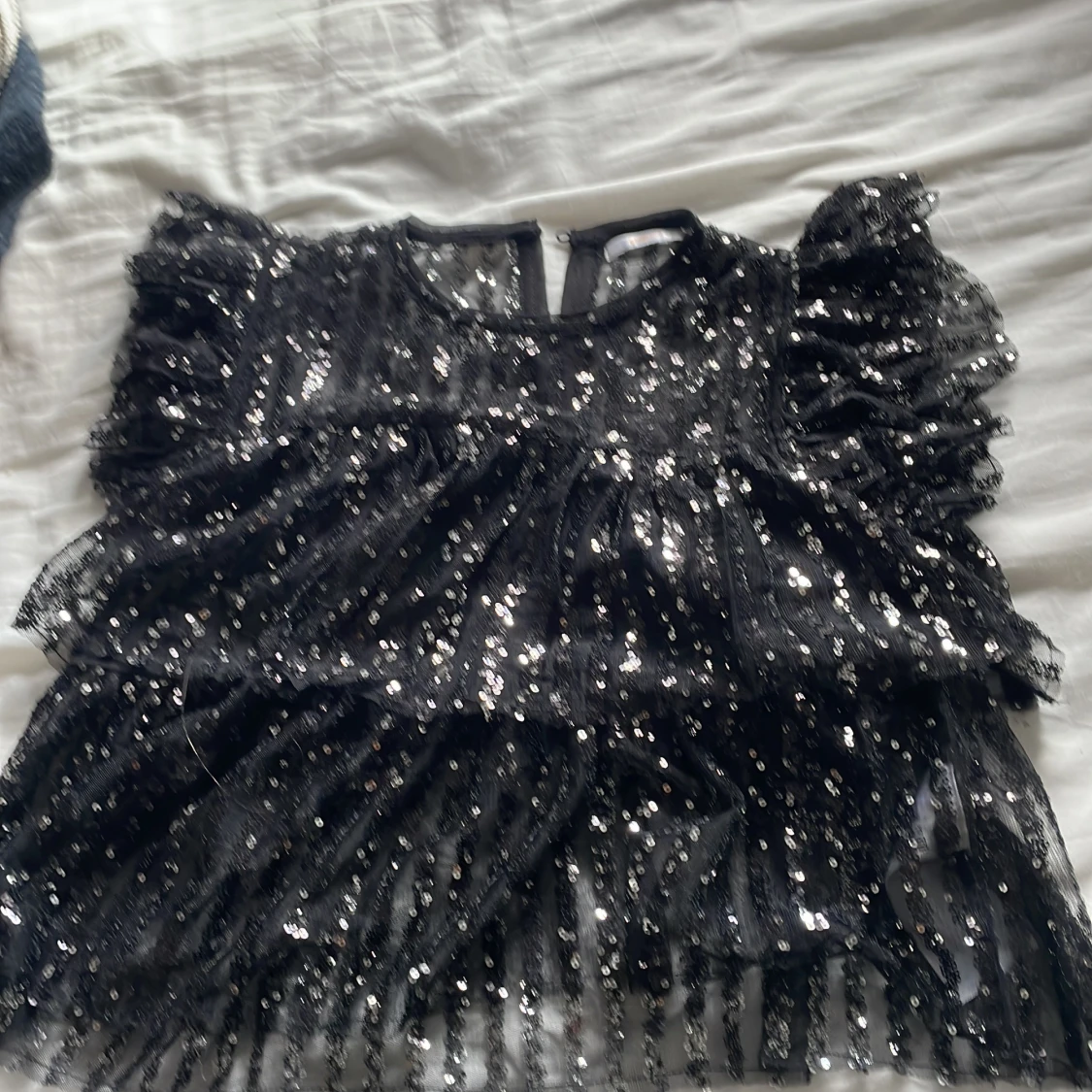 Svart glittrig volangblus Gina Tricot