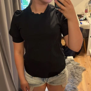 Svart t-shirt med puffärm - Svart t-shirt med korta puffärmar och rund hals. Enkel och stilren modell som passar till det mesta. Mjuk och skön känsla, perfekt till jeans eller shorts.