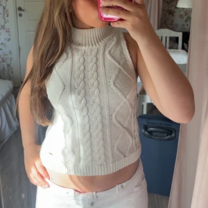 En vit topp  - Säljer en superfin vit stickad topp med kabelstickat mönster. Den är ärmlös och croppad, kommer ifrån Holly& Whyte och är i storlek s💞