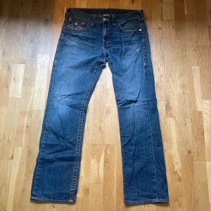 Blåa True Religion jeans  - Blåa jeans från True Religion med orangea sömmar i storlek 34! Skriv gärna för mer bilder på jeansen om de behövs🥰