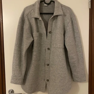 Grå kofta med knappar - Snygg grå kofta med stora knappar framtill och två bröstfickor.