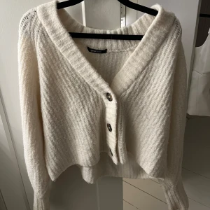Vit stickad kofta från Gina Tricot - Supermysig vit stickad kofta från Gina Tricot med v-ringning och stora knappar.