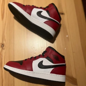 Nike Air Jordan 1 Mid Chicago - Säljer ett par Nike Air Jordan 1 Mid Chicago black toe, i färgerna rött, vitt och svart. Skorna är i ungdomsstorlek 38.  Tillverkade i skinn med vit mellansula och svart yttersula. Perfekt för dig som gillar ikoniska sneakers med streetstyle-vibe.