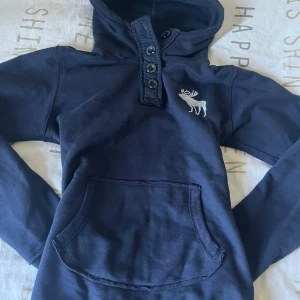 Mörkblå hoodie Abercrombie & Fitch - Snygg mörkblå hoodie från Abercrombie & Fitch med huva, knappar vid halsen och en magficka. passar mig som har s/xs perfekt❤️Lägg gärna bud/offer