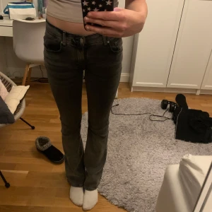 Mörkgrå lågmidjade jeans - Säljer ett par mörkgrå jeans med bootcut-modell och klassisk femficksdesign. Jeansen har låg midja och är i storlek 34