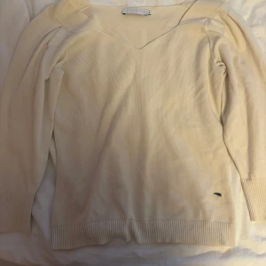 Beige stickad tröja från Coster - Snygg beige stickad tröja från Coster med v-ringad hals och ribbade muddar vid ärmslut och nederkant.