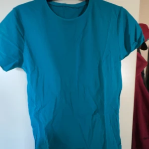 Turkos basic t-shirt  - Enkel turkos t-shirt med rund hals och korta ärmar. Modellen är rak och klassisk, perfekt för en clean och avslappnad stil. Tillverkad i mjuk bomull som känns skön mot huden. Passar dig som gillar färg och vill ha en basic tee i garderoben.
