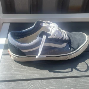 Blå och svarta Vans Old Skool sneakers - Klassiska Vans Old Skool sneakers i blått och svart med vit sula och vit sidosnöre. Ovandelen är i canvas och mocka, med vita skosnören och den ikoniska vågiga Vans-loggan på sidan. Perfekta för en avslappnad streetstil. Pris går och sänkas.. skriv vid minsta fråga ☺️👍🏼
