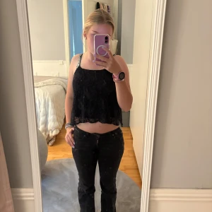 Svart linnetopp  - Svart linnetopp med tunna axelband och vacker spets med blommigt mönster. 