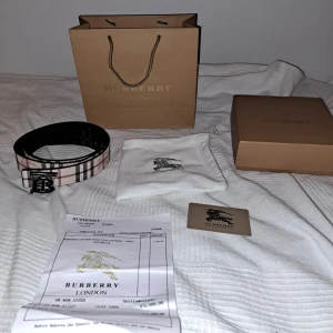 Burberry bälte - TAR EMOT BYTEN‼️Säljer ett klassiskt Burberry bälte i rutigt mönster med ett svart o silverfärgat metallspänne med Burberry-logga. Bältet har en beige bas med svarta, röda och vita ränder. Perfekt accessoar för att lyfta din outfit. Man kan ändra sidor så den blir svart eller beige färgen 