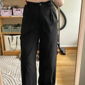 Svarta vida kostymbyxor - Säljer ett par svarta kostymbyxor med hög midja och vida ben. Byxorna har knapp och dragkedja. 