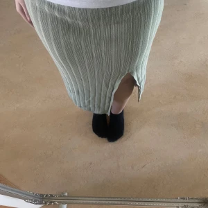 Ljusgrön ribbad kjol med slits - Säljer en ljusgrön ribbad kjol i stickat material. Kjolen har en snygg slits framtill och är midilång med en rak passform. Perfekt för dig som gillar en enkel men trendig stil.
