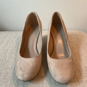 Beige pumps i mocka - Säljer ett par stilrena beige pumps med rund tå och klack. Skorna är i mjuk mocka och har en klassisk design som passar till många olika outfits.