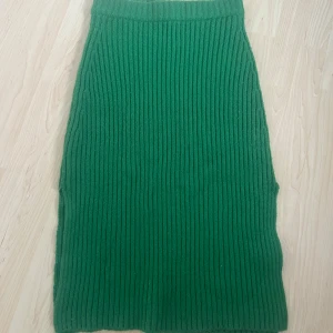 Grön ribbad stickad kjol från Gina Tricot - Säljer en grön stickad kjol från Gina Tricot i storlek M. Kjolen är ribbstickad och har en rak, lång modell som sitter skönt i midjan. Perfekt att styla med en enkel topp eller stickad tröja. Lite nopprig vilket man ser på sista bilden. Färgen stämmer också överens bäst med sista bilderna. 