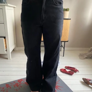 Svarta raka jeansbyxor - Säljer ett par svarta jeansbyxor med rak passform och hög midja. Klassisk femficksmodell med dragkedja och knapp framtill. Perfekta till vardags för en stilren look.