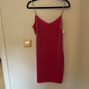 Rosa klänning med glittriga axelband från MNG - Säljer en snygg rosa klänning från MNG med smala glittriga axelband. Klänningen har en enkel, rak passform och är tillverkad i ett slätt material. Perfekt för dig som vill sticka ut med en färgstark look. 