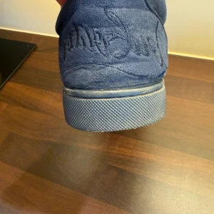Blåa loubitins  - Säljer ett par snygga blå sneakers från Christian Louboutin i mocka med klassisk röd sula och diskret broderad logga på hälen. Skorna har snörning och rund tå, samt en mjuk innersida i beige. Skriv vid funderingar eller prisförslag (pris ej hugget i. sten box och dust bag kommer med också! Tar också emot byten 