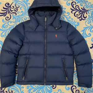 Blå pufferjacka från Polo Ralph Lauren.  - Säljer en blå pufferjacka från Polo Ralph Lauren som inte är använda så mycket. Jackan är 100% äkta och har kvitto fö den. Är ni inte nöjda med priset så skriv bara 