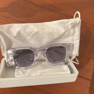 Transparenta solglasögon från CHIMI - Snygga solglasögon från CHIMI med transparent båge och gråtonade glas. Rektangulär form som ger en modern look. Kommer med vit förvaringsask och tygpåse. Perfekta för att lyfta din stil under soliga dagar.