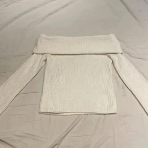 Offshoulder ribbad tröja från H&M - Säljer en vit ribbad offshoulder-tröja från H&M. Tröjan har lång ärm och en bred, vikt krage som sitter snyggt över axlarna. Perfekt för dig som gillar en stilren och trendig look.
