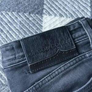 Svarta jeans från Jacob Cohen - Säljer ett par svarta jeans från Jacob Cohen med klassisk femficksdesign och knappgylf. Jeansen har en smal passform och är tillverkade i ett mjukt bomullsmaterial med stretch. Snygga detaljer och diskret logotyp på bakfickan.