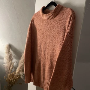 Rosa stickad polotröja från 157 - Mysig rosa stickad polotröja från 157. Tröjan har lång ärm, ribbade muddar och en liten polokrage. Perfekt för kyliga dagar och enkel att styla med jeans eller kjol.