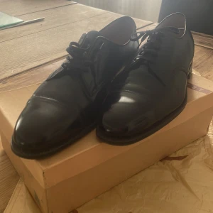 Svarta skinnskor - Klassiska svarta loafers i skinn med snörning och rund tå. Snygg och tidlös design som passar till många olika outfits. Skorna har platt sula och är tillverkade av högkvalitativt läder. Skorna är använda men forfarande i toppform. FEL BOX!! Råka ta bild med fel låda! Så därav osäker på storleken