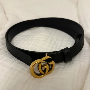 Gucci skärp  - Svart bälte från Gucci med ikoniskt GG-spänne i guld. Det är ca 88 cm långt och 2 cm brett. Har inga synliga tecken på användning. Köpt på Gucci i Stockholm. Nypris 4 200 kr. Kvitto, box och dustbag finns självklart!