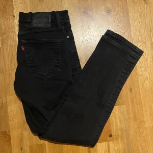 Svarta Levis 511 - Säljer ett par svarta Levis 511 jeans med klassisk femficksdesign och rakt snitt. Jeansen har normal passform och är tillverkade i ett mjukt bomullsmaterial med lite stretch. Perfekta svarta jeans för dig som gillar stilrena och tidlösa plagg. Använda sparsamt. 9/10 skick. Bara att höra av sig för frågor och flera detaljer.