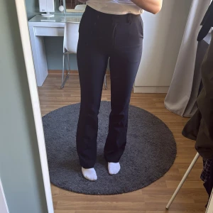 Svarta kostymbyxor från BikBok - Säljer ett par svarta kostymbyxor från BikBok med hög midja och bootcut. Byxorna har klassisk passform och stängs med dragkedja och knapp framtill. Perfekta för en stilren look. Dom är i modellen Wilma tall, jag är 179cm, med långa ben💕