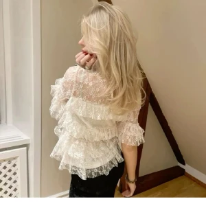 Vit spetsblus med volanger - Säljer en romantisk vit blus i spets med flera lager volanger och trekvartsärm. Blusen har hög hals och transparenta partier. Super fin, inga defekter alls! Den är i storlek M, men passar S också! 