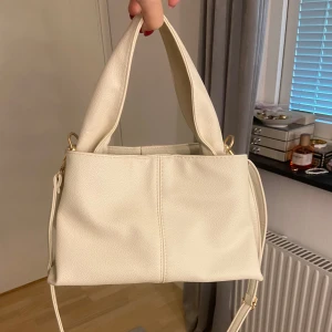 Cremevit handväska - Superfin men har ej fått användning av den. Helt som ny aldrig haft något i den eller ens använt den. Det längre bandet går att ta av om man vill. Får plats med mycket!☺️