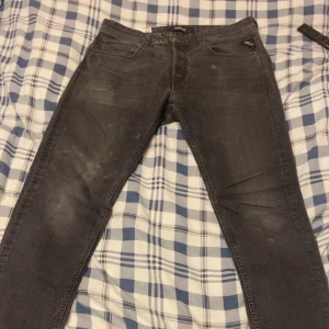 Mörkgrå Replay Grover jeans - Säljer ett par grå jeans från Replay, modell Grover. Klassisk femficksdesign med knapp och dragkedja i gylfen. Jeansen har raka ben och diskreta slitningar för en cool look. Perfekta till vardags och passar till det mesta. Pris kan diskuteras.