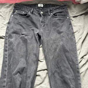 Svarta jeans från 157 - Ett par svarta jeans från märket 157. Byxorna har en låg midja och en rak passform. De har fem fickor och en knappgylf. Tyvärr är dom lite slitna/trasiga längst ner (se bild)